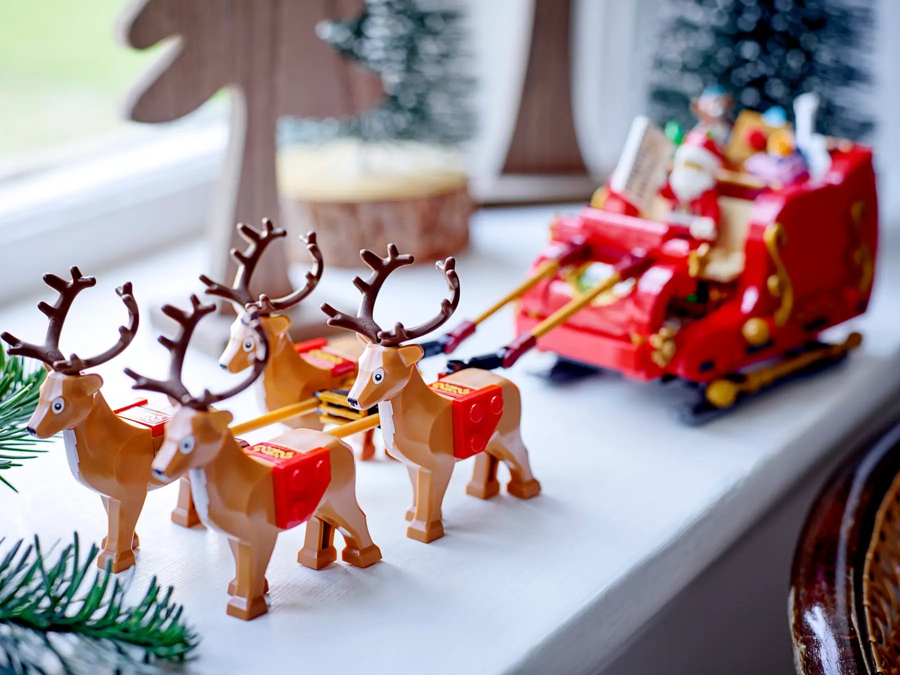 Toy reindeer pulling a toy sleigh with Santa Claus on a Christmas-themed background.